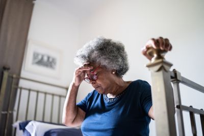 A woman sitting on the bed because she is dizzy