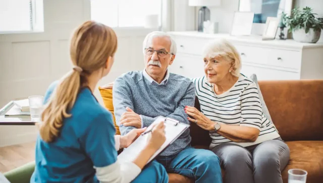Elderly couple talking with a nurse at home.