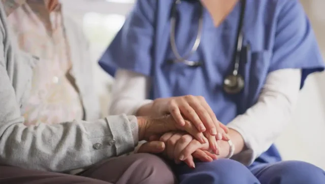 A nurse holding the hands of an elderly patient.
