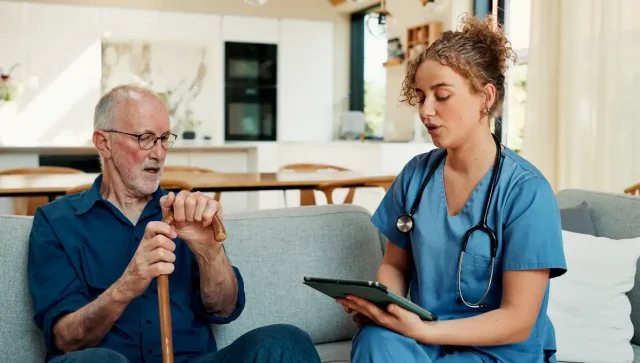 Nurse with senior man for medical checkup at home.