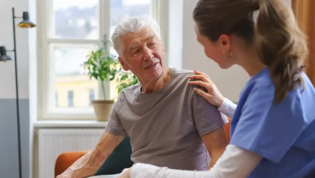 Female nurse checking on an elderly senior in his home.