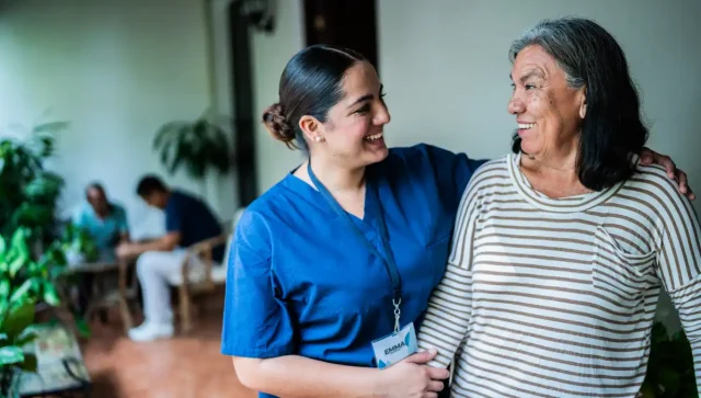Smiling nurse helping elderly patient.
