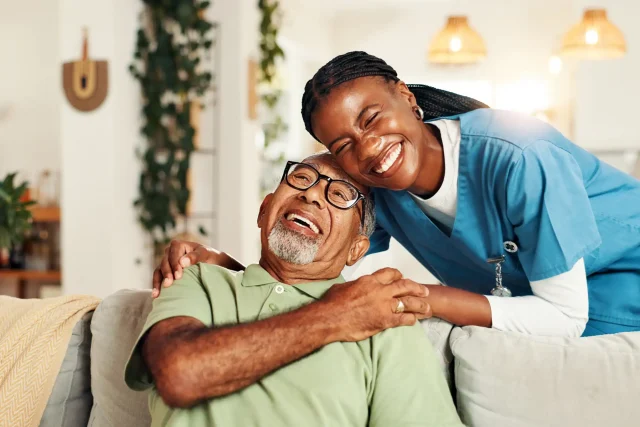 Smiling nurse and patient in a home setting.