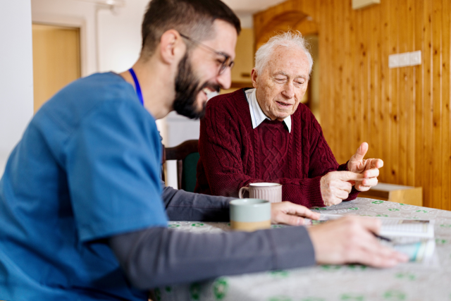 Home health nurse with a senior man enjoying coffee.