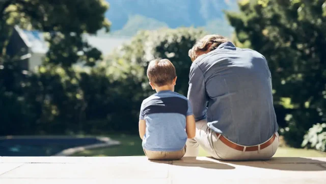 Father comforting a sad son while they sit outside.