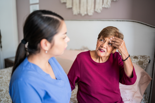A woman nurse speaking with a patient who has dementia