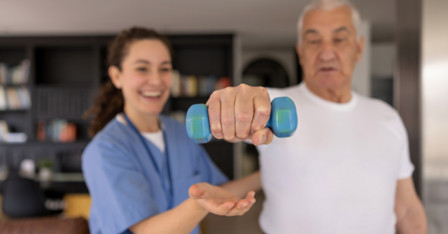 Home health nurse supports older man with physical therapy during stroke recovery at home, promoting strength and independence.
