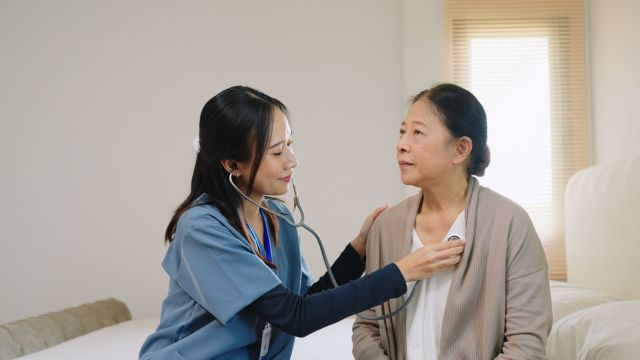 Hospice nurse listening to patients heart