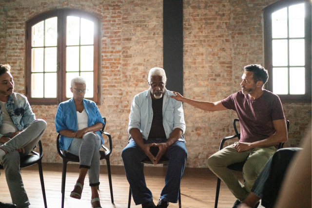 Man receiving comfort during a grief support group meeting.