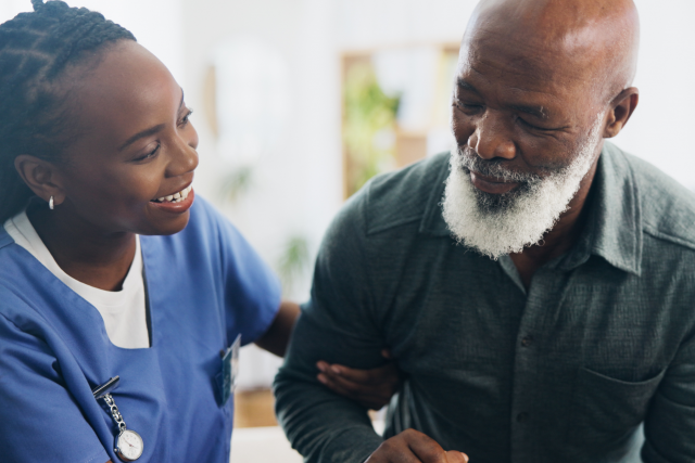 A home health nurse helping a man walk around his home