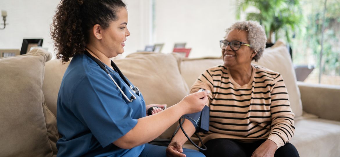 Healthcare worker taking blood pressure of senior woman at home